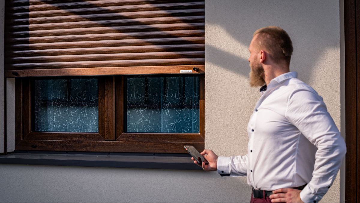  Ein Mann schließt die Außenrollläden mit einer Fernbedienung
